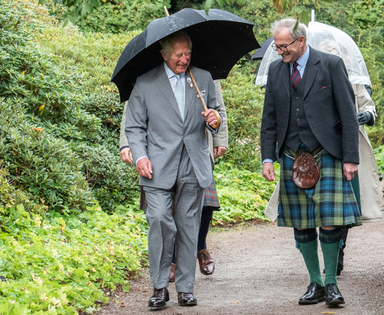 Two men talking and walking down a garden path