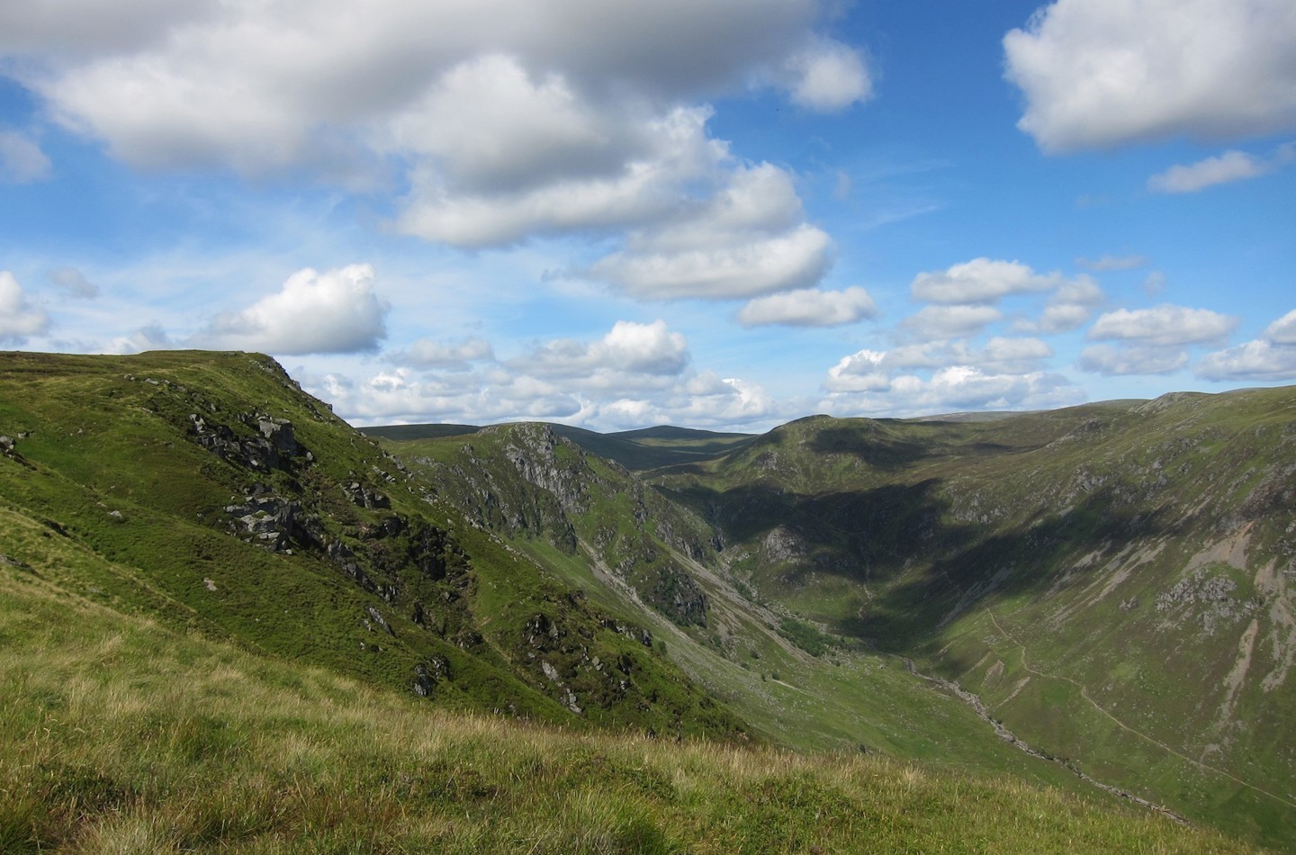 Expansive view across mountains with blue sky and light cloud