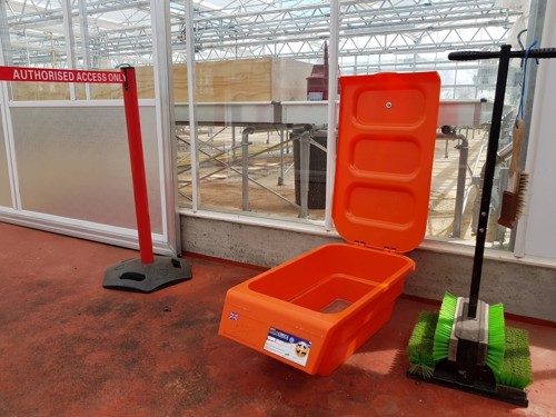 A footbath and brush sit next to an access barrier