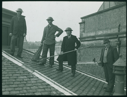 Men in helmets stand on a sloping roof