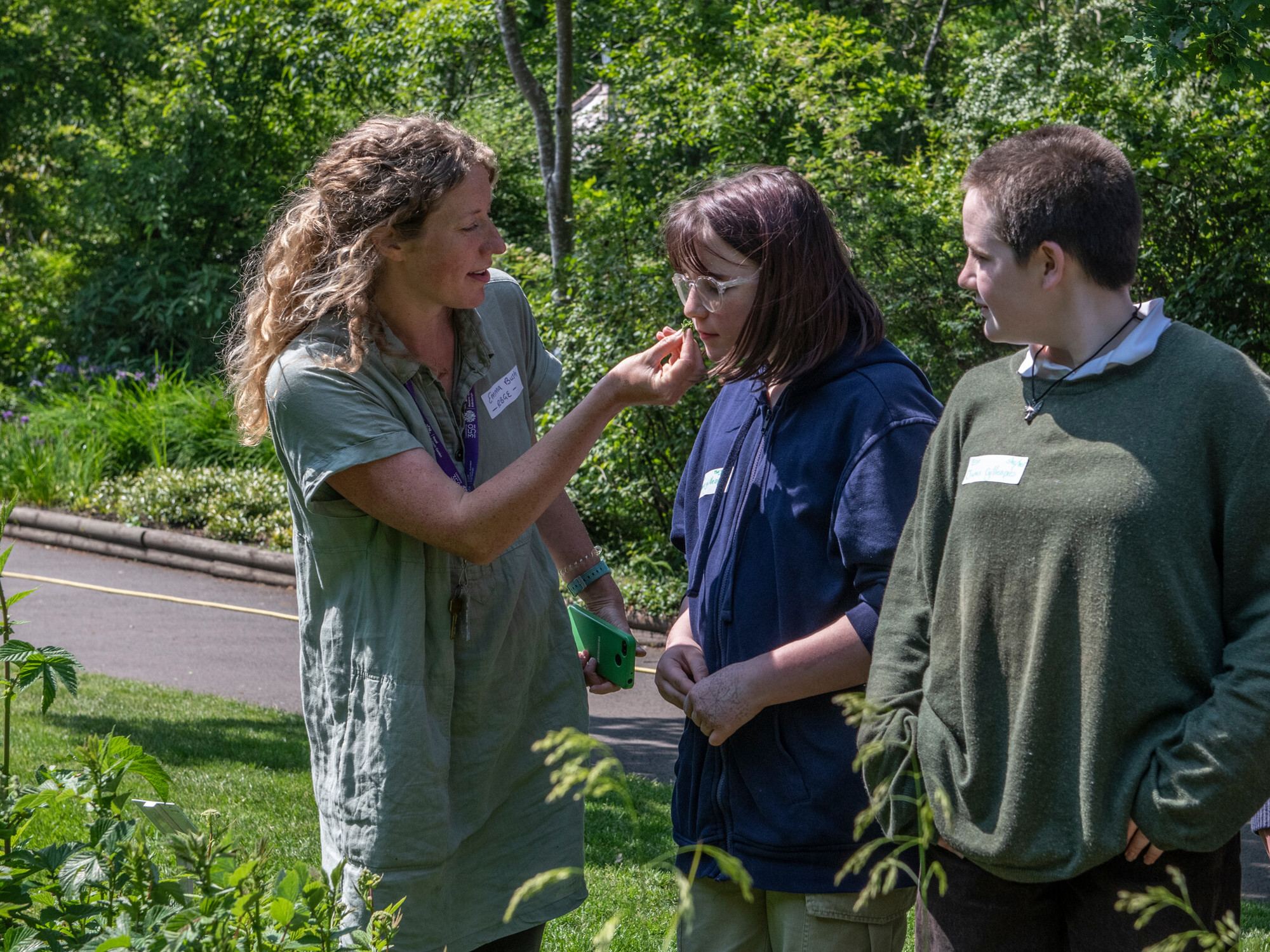 A member of the Botanics offers two young visitors a closer look at the some plants