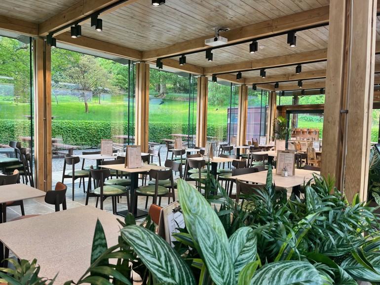 An empty cafe with large windows with views to a garden